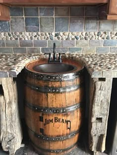 a wooden barrel sink in front of a brick wall and stone counter top with the words j m beam written on it