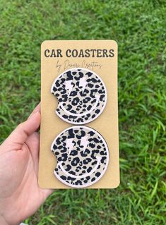 a person holding up a pair of car coasters in front of the camera on some grass