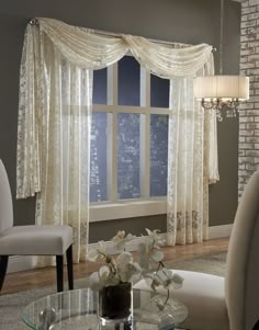 a living room filled with furniture and a window covered in white sheer curtained drapes