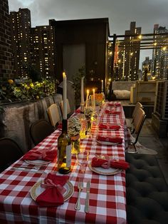 a long table with red and white checkered cloths is set for an outdoor dinner