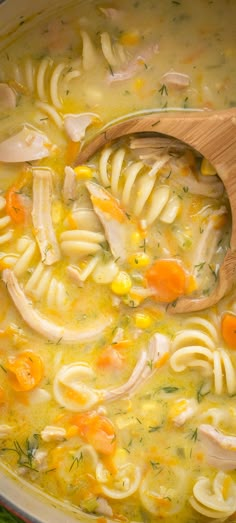 a wooden spoon in a pot filled with chicken noodle soup