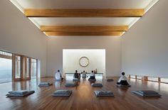 there are many people sitting on the floor in this yoga room with their backs to each other