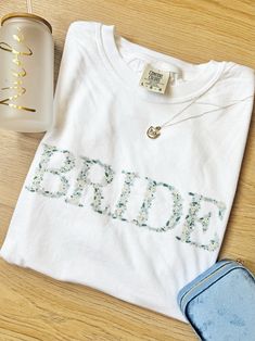 a white t - shirt with the word bride on it next to a pair of blue jeans