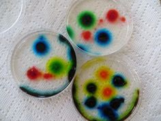 three glass buttons with multicolored designs sitting on top of a white table cloth