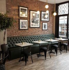 an empty restaurant with green booths and tables in front of large windows that have pictures on the wall