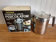 a stainless steel percolator next to a boxed box