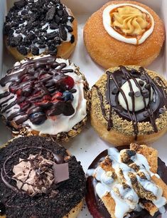 a box filled with different flavored donuts covered in frosting and toppings