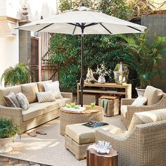 an outdoor living area with wicker furniture and white umbrella over the couches,