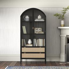 a room with a fireplace, bookshelf and rug on the floor