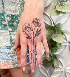 a woman's hand with a flower tattoo on it