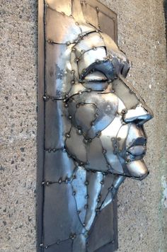 a metal sculpture on the side of a building with rivets covering it's face