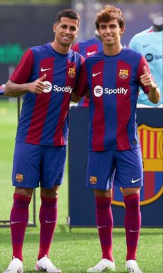 two soccer players are standing on the field posing for a photo with their arms around each other