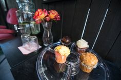 three cupcakes are sitting on a clear plate next to a vase with flowers