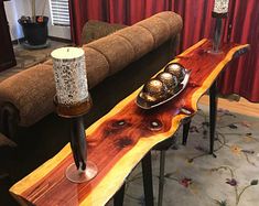 a wooden table with candles on it in front of a couch and red drapes