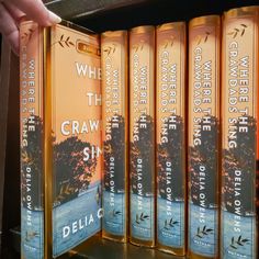 a person is holding a book in front of a row of books on a shelf