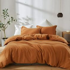 a bed with an orange comforter and pillows