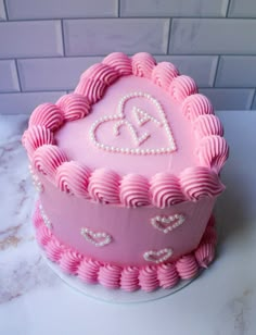 a pink heart shaped cake sitting on top of a counter