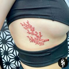 a woman's stomach with red coral tattoo on her belly and under the breast