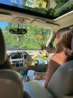 a woman sitting in the driver's seat of a car holding a yellow sign