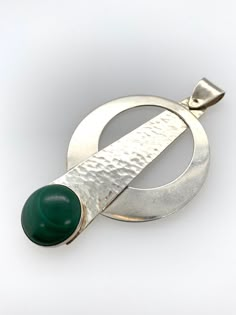 "Vintage Modernist Pendant -Unique and modern, circular pendulum design -Comprised of Sterling silver and a round bezel set malachite stone -The silver piece holding the malachite is hammered or textured, the circular piece and bail are not -Marked \"Sterling\" on the back -Bail is connected with a single pin and swivels -Larger bail to accommodate most chains, .25\" x .1\" teardrop shaped opening -Pendant measures about 2.5\" x 1.5\" -Malachite stone measures 14mm round -Total weight 9.6g -Pend Modern Cabochon Round Pendant Jewelry, Modern Jewelry With Round Cabochon Pendant, Modernist Round Cabochon Jewelry, Modern Cabochon Round Pendant, Modern Polished Emerald Jewelry, Modern Green Malachite Jewelry, Modern Cabochon Jewelry, Modern Green Cabochon Jewelry, Modern Green Pendant Jewelry