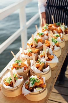 several small baskets filled with food on top of a wooden table next to the water