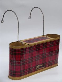 a red and black checkered box with two metal hooks on the top of it