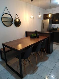 a dining table and chairs in a room with lights on the wall above it, next to a kitchen counter