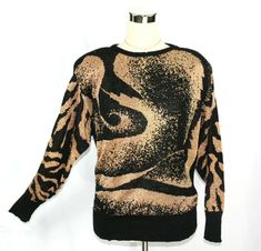 Gorgeous vintage 1980's sweater from TJW of Mervyn's featuring an artistic swirl and tiger stripes pattern in metallic gold and black.  ~Light shoulder padding ~Ribbed cuffs, hem, and neckline There is no "ingredients" tag so I am only guessing that it's made of acrylic due to the feel and the vintage of the knit. There is also no size tag. It fits closest to a smallish-medium. Please see measurements below.  This sweater is in excellent vintage condition and is ready for you to rock it!   Measu