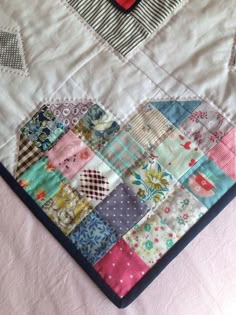 a close up of a quilt on a bed with a red heart in the middle