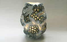 a white vase with some lights inside of it's center and an intricate design on the outside