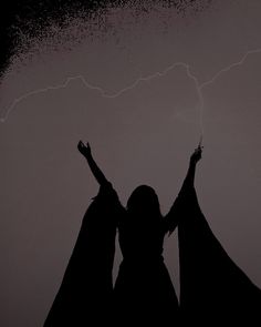 two people standing in the dark with their arms raised and one person holding up her hands