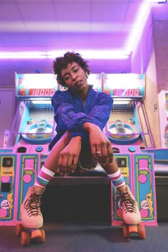 a young man sitting on top of a table next to a pinball game machine