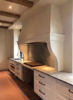 a kitchen with white cabinets and an oven in the center, along with wood flooring