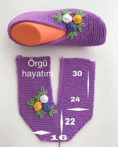 an object made out of knitted material with flowers and leaves on the side, next to a ruler