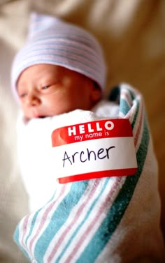 a baby wrapped in a blanket with a name tag