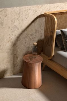 a wooden table sitting next to a bed in a room with beige walls and flooring