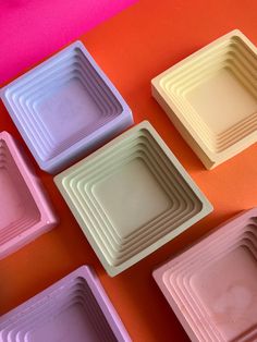 several square trays are arranged on an orange and pink surface