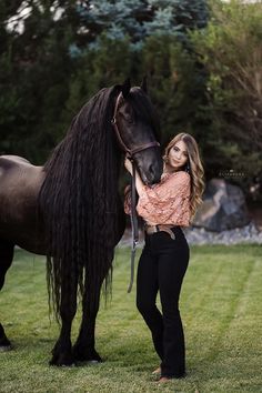 a woman standing next to a black horse