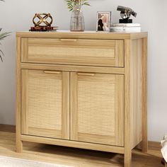 a wooden cabinet with wicker doors and drawers in a room next to a potted plant