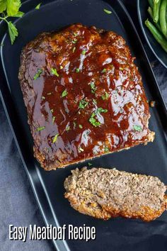 meatloaf with sauce and green beans on a black platter