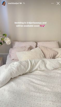 a bed with white sheets and pillows in a bedroom next to a vase filled with flowers