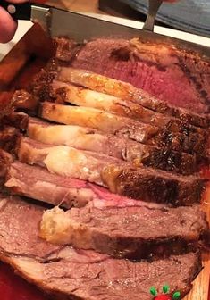 someone cutting up some meat on top of a wooden board with christmas decorations around it