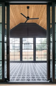 an open door with a ceiling fan in the center and windows on both sides, leading to a patio area