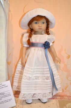 a doll with red hair wearing a white dress and hat