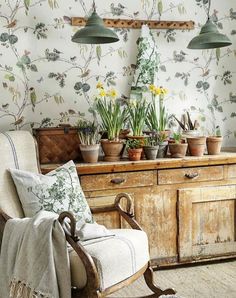 an old wooden dresser with potted plants on it and two green lamps hanging from the ceiling