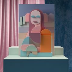 an abstract paper sculpture on display in front of pink curtains