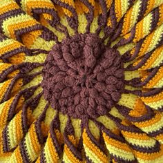 a close up view of a crocheted flower in brown, yellow and white