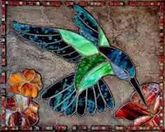 a stained glass hummingbird flying over flowers