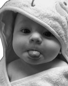 a black and white photo of a baby wrapped in a towel looking at the camera