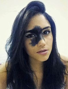 a woman with black face paint on her face and long dark hair is posing for the camera